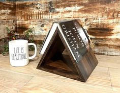 a wooden stand with a coffee cup and book on it sitting next to a wood wall