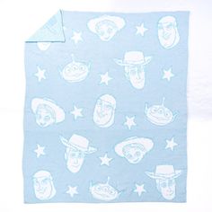 a blue and white blanket with cartoon heads on it, stars and moon shapes in the sky