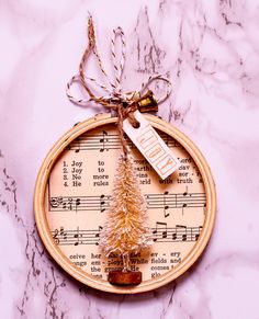 an ornament with a christmas tree on top of sheet music and a bell