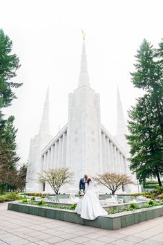 a bride and groom standing in front of the mormon temple at their wedding day,