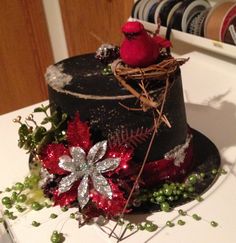 a red bird sitting on top of a black hat with silver and red decorations around it