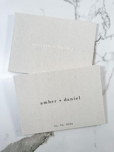 two business cards with the words amber and daniel printed on them sitting on a marble surface