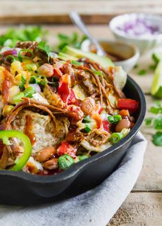 a skillet filled with chicken, rice and veggies on top of a wooden table