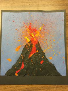 a piece of paper with paint splattered on it and a volcano in the background