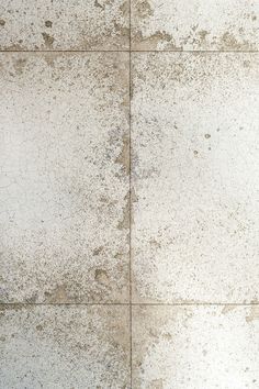 an old cement floor with white and brown spots on the tile, as well as some dirt