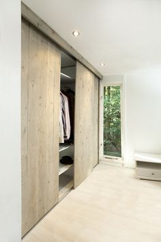 an open closet with clothes hanging on the doors