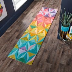 a colorful runner rug on the floor next to a potted plant