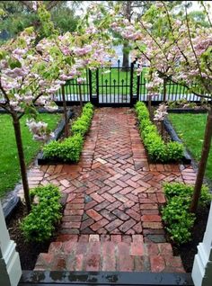 a brick walkway with trees and flowers in the background