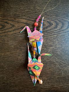 an origami dragon is hanging on a string with beads and beads attached to it