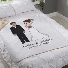 a bed with a white comforter that has an image of a bride and groom on it