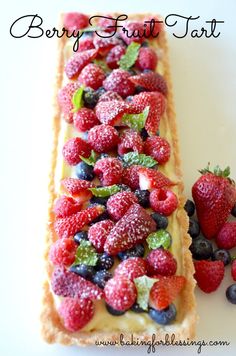 a pastry with berries and mint on it next to some strawberries, blueberries and raspberries