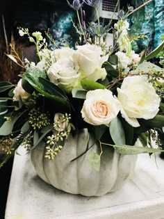 a white pumpkin filled with flowers on top of a table