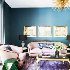 a living room with two couches, chairs and a coffee table in front of a blue wall