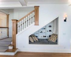 a dog bed in the corner of a room under a stair case with pillows on it