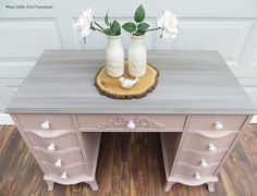 two white vases sitting on top of a wooden table next to a pink dresser