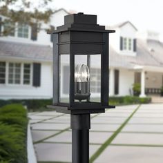 a black post light in front of a large house with two lights on each side