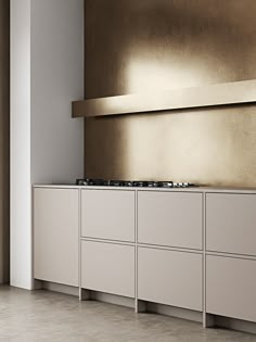 an empty kitchen with white cabinets and gold wall