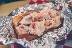 there is a sandwich with shrimp on top of it in foil wrapper and some ketchup