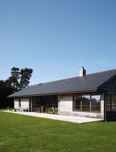 the house is made out of wood and has grass in front of it, as well as an open lawn area