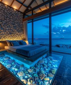 a bedroom with an aquarium bed in the middle and ocean view through glass windows at night