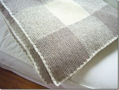 a white and gray blanket sitting on top of a bed