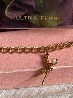 Sweet dainty ballerina with pearl dangles from a 6 1/2" textured chain bracelet for the young lady.   Snap box clasp. Tiny goldtone links are delicately textured. Tiny ballerina charm has a textured tutu.   In an extended arm is a small pearl which is referred to as a 'cultra pearl'.  I'm not sure what that means. If you have a young lady who is started ballet or pursuing ballet for years, this might be the way to start a charm bracelet.   Add ballet shoes charms.   A tiny crown.   And perhaps individual dangling pearls. Charm is 1/2" top to bottom. Vintage Gold Bracelets With Dangling Charms, Ballet Core Jewelry, Vintage Adjustable Charm Bracelet With Dangling Charms, Ballet Necklace, Ballet Charm Bracelet, Vintage Ballerina, Ballet Girls, Shoe Charms, Ballet Shoes