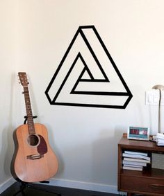 an acoustic guitar sitting in front of a wall with the letter a on it's side