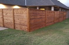 a wooden fence in front of a house with lights on the top and bottom half