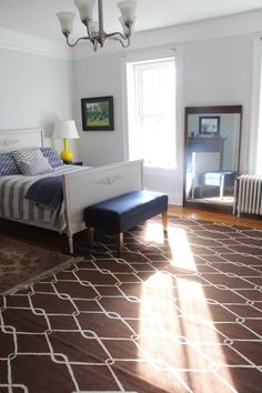 a bed sitting on top of a brown rug in a bedroom next to a window