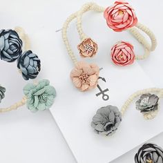 several different flower hair clips on top of a white table next to an open book