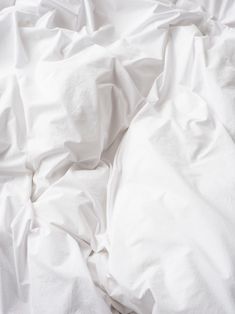 an unmade bed with white sheets and pillows