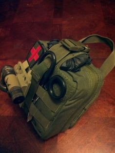 a green bag with some items in it on a wooden table next to a pair of binoculars