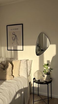 a bedroom with a bed, mirror and plant on the side table in front of it