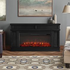 an electric fireplace in a living room with a painting on the wall and a chair next to it