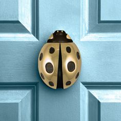 a ladybug door knocker on the side of a blue door with black polka dots