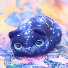 a blue stuffed animal with stars on it's head and eyes sitting on a colorful surface