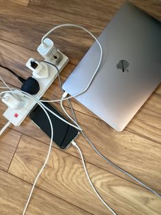 an apple laptop is plugged in to a charger on the floor with cords