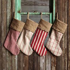 three christmas stockings hanging on a wooden wall with an old window in the back ground