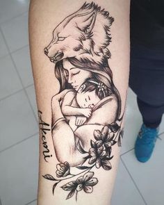 a woman with a wolf tattoo on her arm holding a small child in her arms