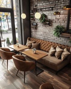 a living room with couches, tables and chairs in front of a brick wall