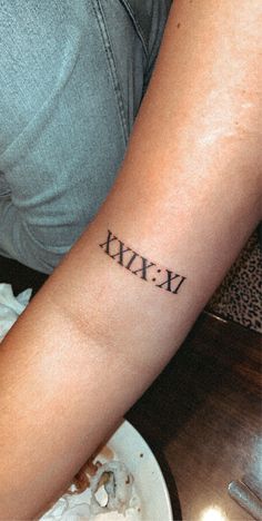 a woman with a tattoo on her arm that says xixu in roman numerals