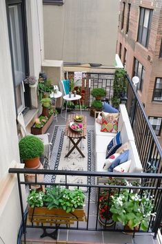 an apartment balcony with potted plants and furniture