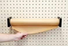 a person is holding a roll of paper in front of a pegboard