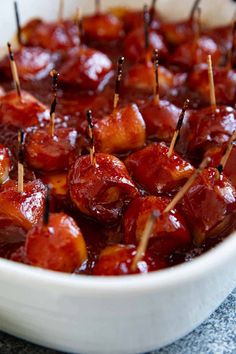 a white bowl filled with lots of food on top of a blue table cloth and wooden skewers sticking out of it