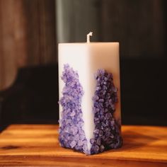 a white candle with purple flowers on it