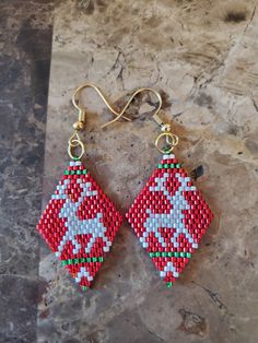 two red and green beaded earrings on a marble surface