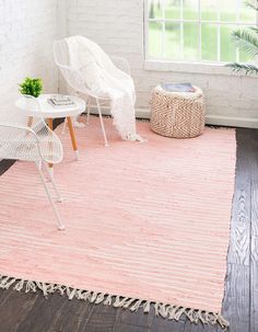 a living room with white furniture and pink rugs on the hardwood floor, along with a large window