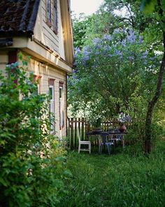 an outdoor table and chairs in the grass next to a house with trees around it