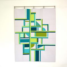 a white wall with a green and blue quilt hanging on it