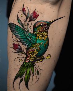 a colorful hummingbird tattoo on the side of a woman's thigh